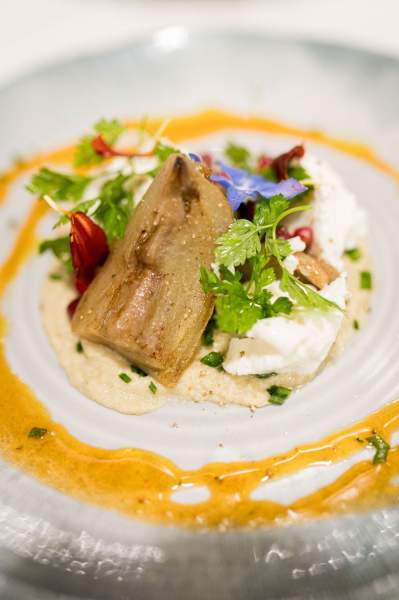 Plat gastronomique du restaurant La Table d’Elka, composé de viande, d’herbes fraîches et de sauce colorée présentée en cercle sur l’assiette.