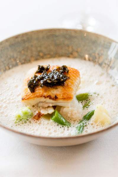 Plat de poisson servi au restaurant La Table d’Elka, garni de légumes verts et nappé d’une émulsion crémeuse.