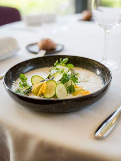 Assiette de soupe froide ou velouté garnie de légumes et herbes fraîches, servie au restaurant La Table d’Elka.