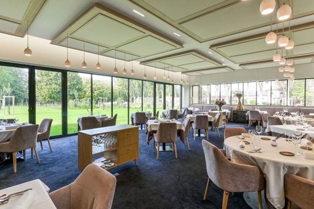 Grande salle du restaurant La Table d’Elka, lumineuse et élégante, avec vue sur le jardin grâce à de larges baies vitrées.