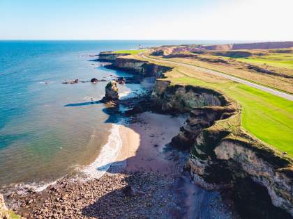 Vue aérienne des falaises et du littoral de Normandie, non loin du restaurant La Table d’Elka, avec la mer et la plage en contrebas.