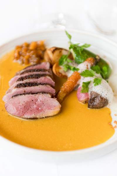 Plat principal du restaurant La Table d’Elka, composé de magret de canard tranché, légumes rôtis et sauce onctueuse à l’orange.