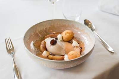 Dessert du restaurant La Table d’Elka, composé de crème glacée, de choux garnis et de sauce caramel disposés dans une assiette creuse.