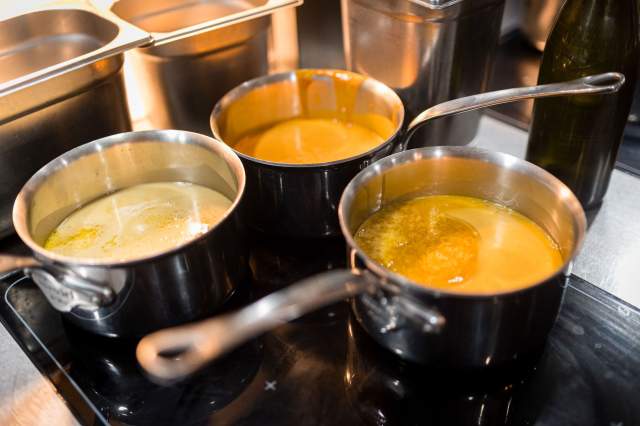 Casseroles de sauces colorées en préparation sur le plan de cuisson du restaurant La Table d’Elka.