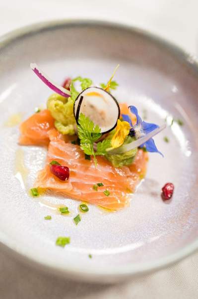 Entrée raffinée du restaurant La Table d’Elka, composée de saumon mariné, de légumes croquants et de fleurs comestibles colorées.