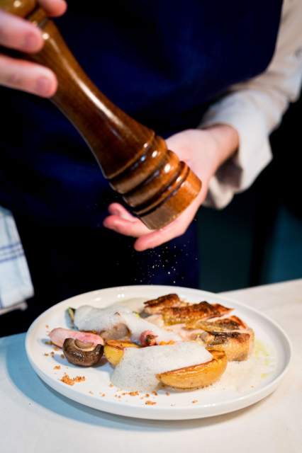 Assaisonnement d’un plat au poivre au restaurant La Table d’Elka, un cuisinier utilisant un moulin à poivre au-dessus d’une assiette dressée.