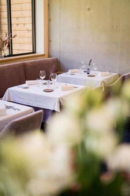 Tables dressées dans un espace cosy du restaurant La Table d’Elka, avec nappes blanches, verres et lumière naturelle douce.