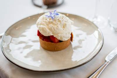 Dessert du restaurant La Table d’Elka, tartelette aux fraises surmontée de crème légère et décorée d’une fleur comestible violette.