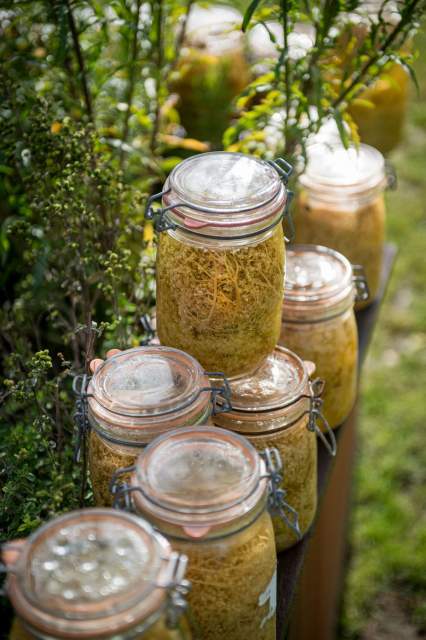 Pots en verre remplis de conserves maison alignés dans le jardin du restaurant La Table d’Elka, sous la lumière naturelle.